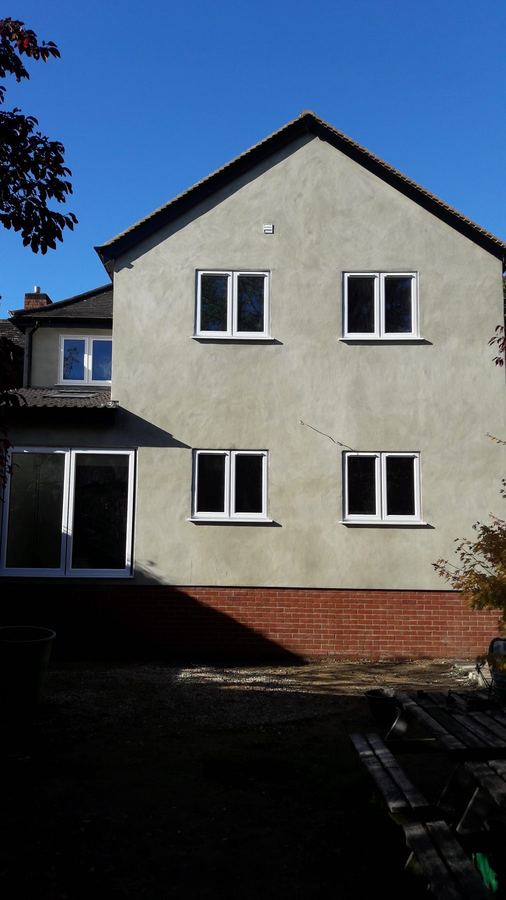 Rendered two storey gable side extension with a brick plinth