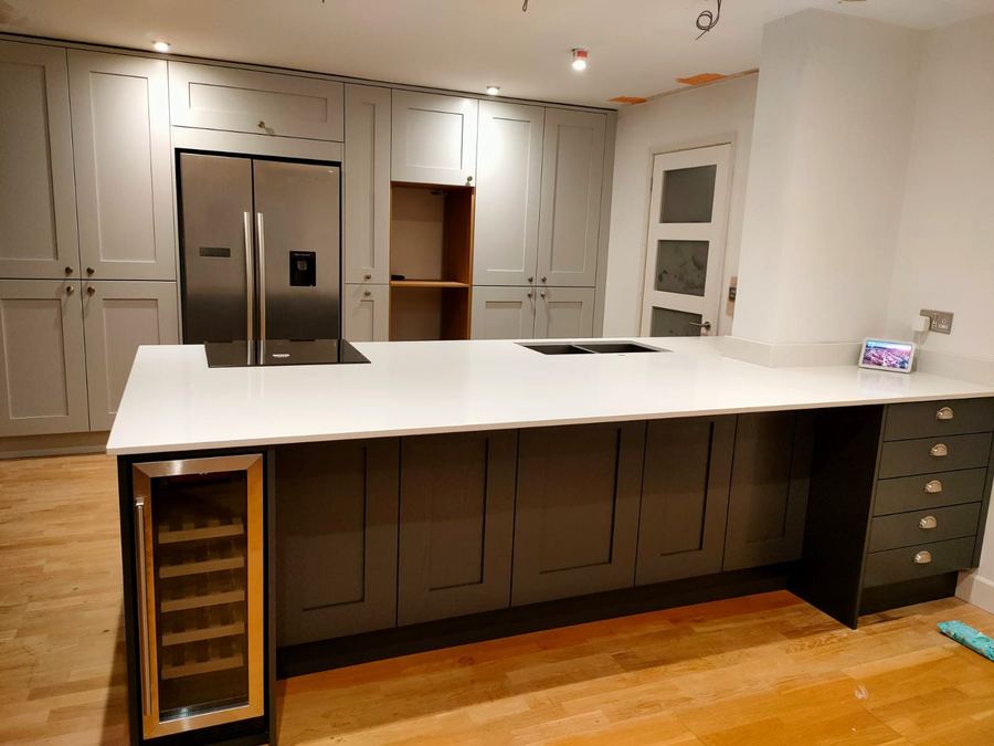 Shaker kitchen with a peninsula, white quartz worktop and wine cooler
